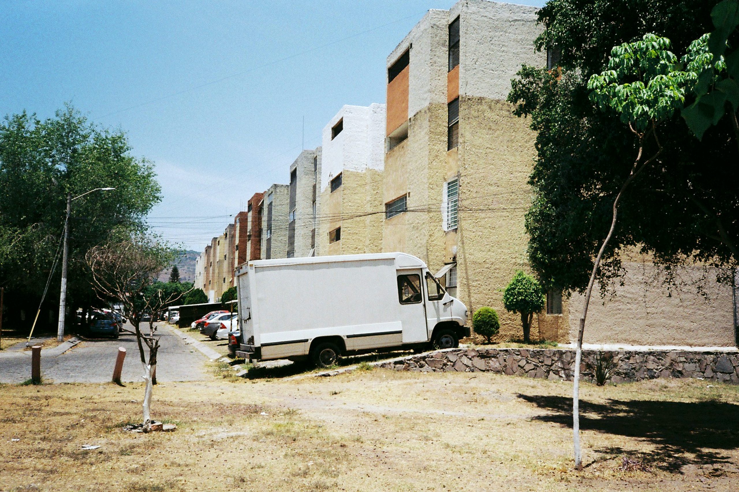 white van parked beside brown concrete building during daytime